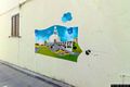 Girasole-Il murale intitolato Io speriamo che me la cavo che rappresenta un paesaggio con architettura e formiche