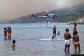 Sant’Antioco-Incendio a Coaquaddus: elicottero della Protezione Civile che fa rifornimento tra i bagnanti